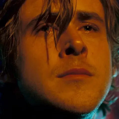 Лицо молодого человека крупным планом, по его щеке стекает слеза, взгляд направлен вверх.