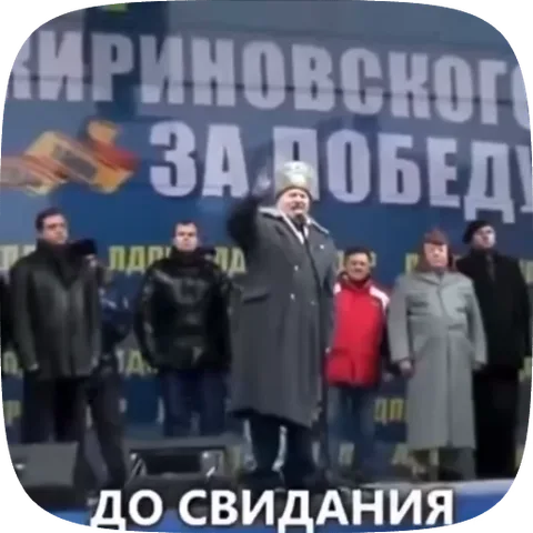 Политик в шапке и пальто машет рукой перед баннером, внизу меняются надписи.