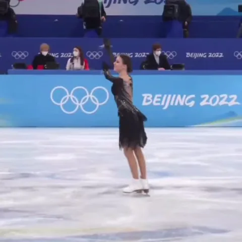 Фигуристка в черном платье кружится на льду во время выступления.