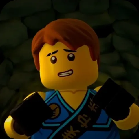 Анимация персонажа Джея из LEGO Ninjago в синем кимоно, который разводит руками с растерянным лицом на фоне каменной стены.
