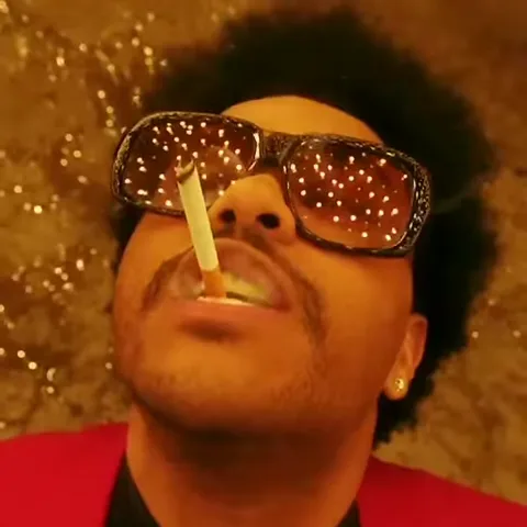 Анимация с певцом The Weeknd, который курит сигарету, держа её губами, в больших блестящих очках и красном пиджаке.
