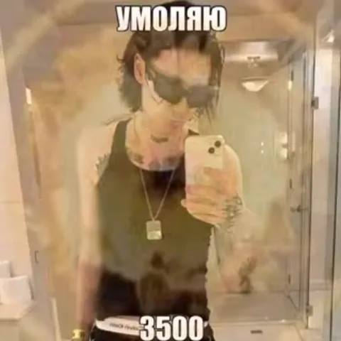 Молодой человек с татуировками и в темных очках фотографирует себя на телефон в ванной комнате. На видео поверх наложены эффекты частиц и надписи.