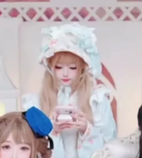 Анимация с двумя девушками в стиле лолита: одна в белом платье и чепце держит телефон, вторая в синем берете видна частично.