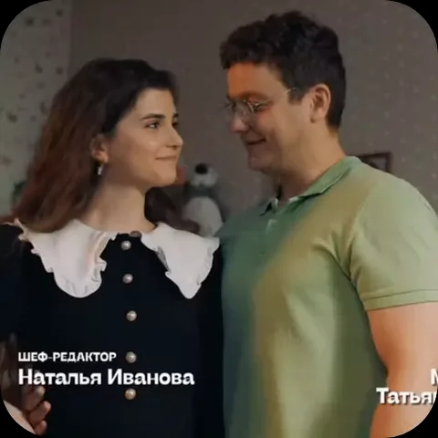 Брюнетка в черном платье с белым воротником и парень в очках и зеленой футболке нежно улыбаются, глядя друг на друга.