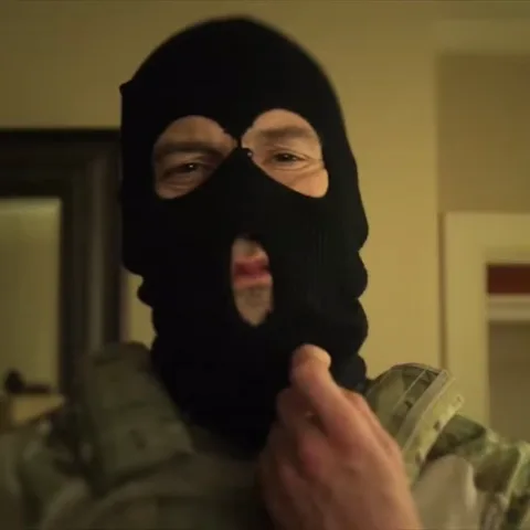 Анимация, где Джон Бернтал в военной экипировке снимает с головы черную вязаную маску-балаклаву.