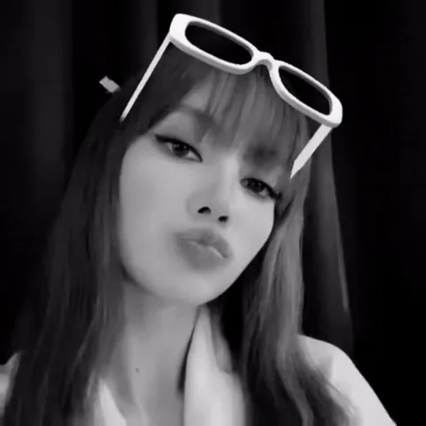 Чёрно-белое видео Лизы из BLACKPINK с белыми очками на голове, она делает губы уточкой.