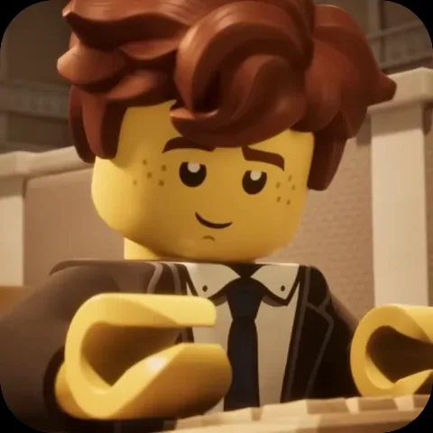 Анимация персонажа Джея из LEGO Ninjago в деловом костюме, который работает за компьютером.