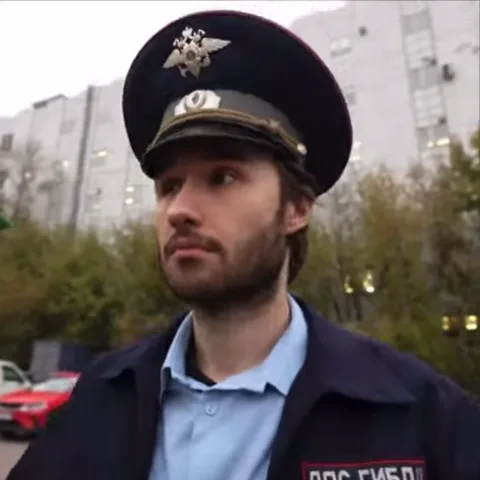 Гифка с мужчиной в полицейской фуражке и куртке ДПС ГИБДД. Он делает жест рукой, изображая телефонную трубку у уха, и кивает.