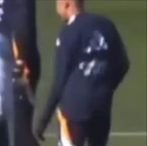 Игрок в футболке с логотипом Adidas выполняет смешной танцевальный шаг во время тренировки.