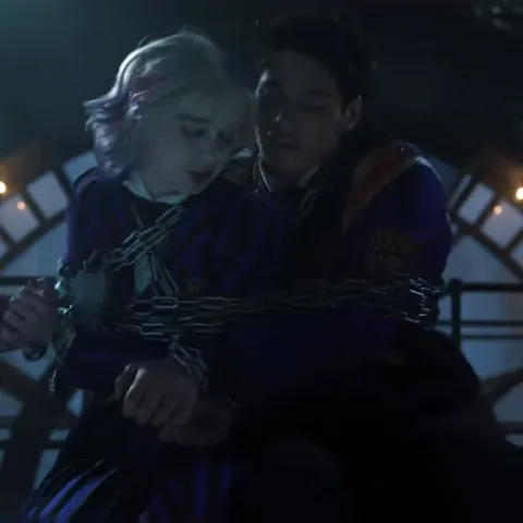 Анимация из сериала «Уэнсдей», где Энид Синклер и Пугсли Аддамс связаны цепями и реагируют на происходящее.