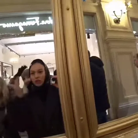 В отражении зеркала видны девушки, которые смотрят на себя и поправляют прически.