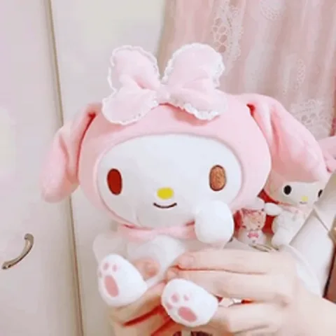 Розовая плюшевая игрушка кролика с бантом на голове машет ушами.