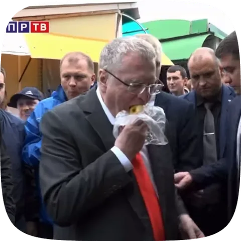 Анимация мужчины в сером костюме и красном галстуке, который ест что-то из пакета на улице.