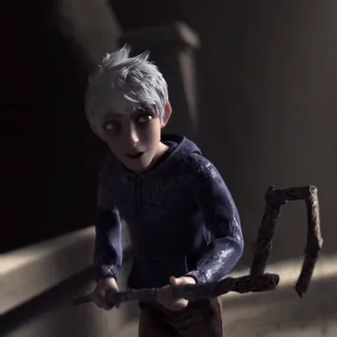 3D-персонаж с короткими белыми волосами, одетый в темно-синюю толстовку. Он наклонился вперед, опираясь на грубый деревянный посох, и смотрит на зрителя.