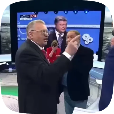 Мужчина в очках и темном костюме на телевидении эмоционально указывает пальцем и машет рукой.