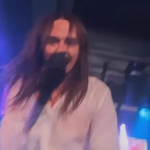Анимация показывает музыканта Tommy Cash во время выступления: он держит руку у лица в чёрной перчатке и смотрит в камеру.