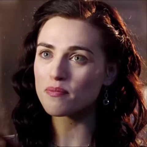 Анимация крупного плана женщины с темными кудрявыми волосами, которая смотрит прямо перед собой и удивленно приоткрывает рот.