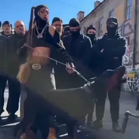 Девушка выгуливает собаку в окружении группы людей в масках.