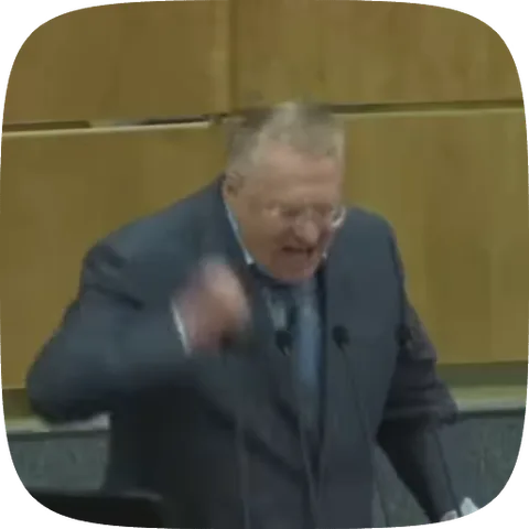 Политик Владимир Жириновский в костюме активно жестикулирует во время выступления на трибуне.