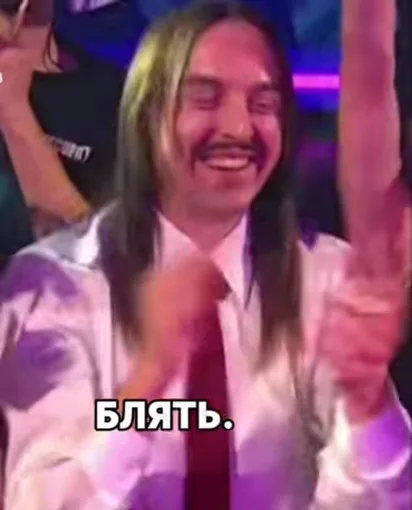 Улыбающийся мужчина с длинными волосами в рубашке хлопает в ладоши на фоне зала, внизу крупная белая надпись.