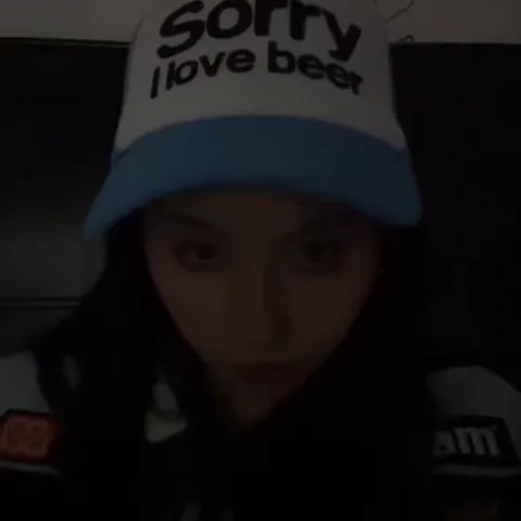Крупный план девушки в кепке с текстом «Sorry I love beer», которая меняет направление взгляда с опущенного на прямой.