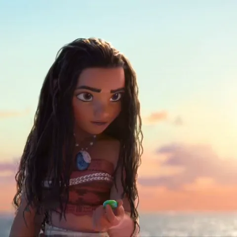 Моана, персонаж Disney, смотрит на зеленый камень в своей руке, выражение лица меняется от сосредоточенности до удивления и улыбки.