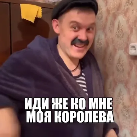 Мужчина в полосатой майке и кепке с искусственными усами делает зазывающий жест рукой на фоне обоев.