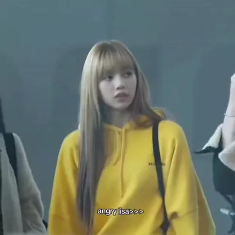 Девушка в жёлтом худи с надписью 'angry lisa' на фоне серой стены.