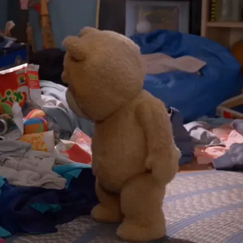Анимация с персонажем Ted из фильма «Тед», который поднимает носок в беспорядке одежды.