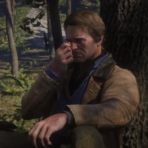 Анимация персонажа игры Red Dead Redemption II: мужчина в коричневой куртке сидит на земле, опираясь спиной о дерево. Сначала он закрывает лицо рукой, растирая глаза, затем убирает руку и смотрит вверх с грустью.