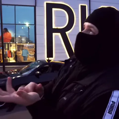 Анимация парня в маске, который энергично жестикулирует руками перед магазином.