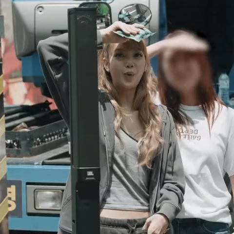 Анимация с Лизой из BLACKPINK, которая смеется и промокает лоб во время съемок на улице.