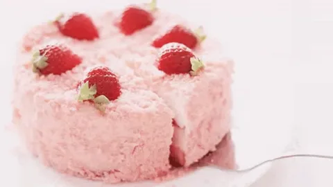 Розовый торт с клубникой разрезают лопаткой.