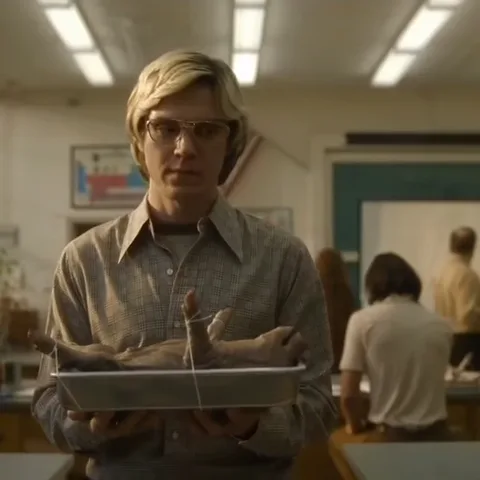 Анимация из сериала: молодой человек в очках держит поддон с препарированным животным в школьном кабинете биологии.