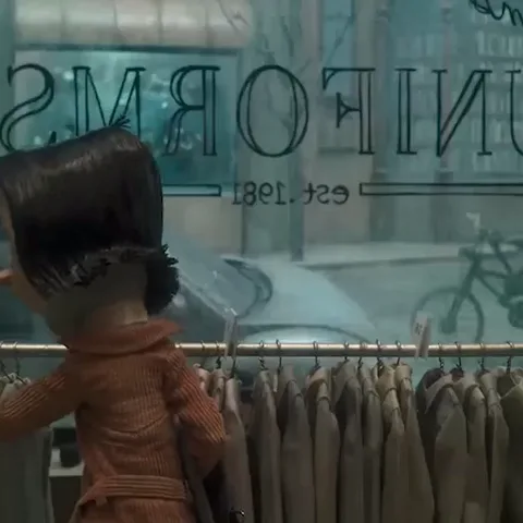 Стикер с персонажем Коралиной из одноимённого мультфильма. Она стоит у витрины магазина униформы, разглядывает одежду и поворачивается к зрителю.