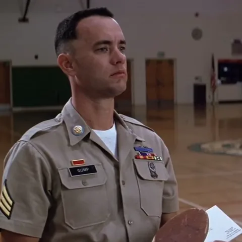 Мужчина в военной форме с нашивкой GUMP держит медаль и смотрит прямо перед собой.