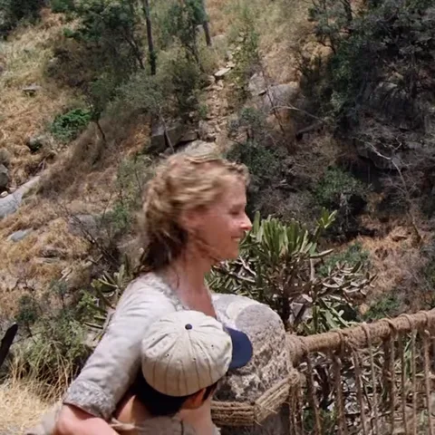 Девушка с ребёнком на подвесном мосту, улыбается.