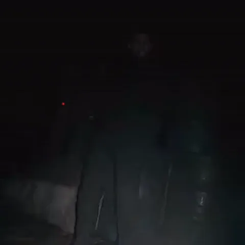 Анимация Криса Редфилда из Resident Evil, который стоит в полумраке и оглядывается.