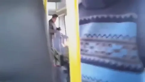 Видео из салона автобуса: молодой человек в куртке сидит на месте и размахивает руками перед камерой.