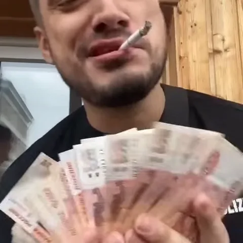 Мужчина с сигаретой показывает веер из российских рублей