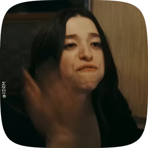 Девушка с надутыми щеками и недовольным выражением лица, пытается что-то съесть.